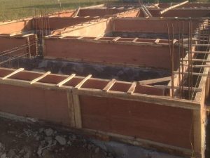 Proses pemasangan bekisting kayu untuk membuat sloof bangunan